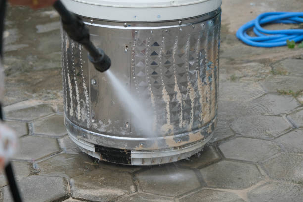 Close-up of washing machine drum being descaled with high-pressure cleaner with parts removed.