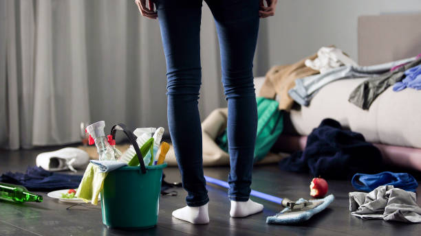 Woman shocked by the post-party mess in her apartment, emphasizing the need for professional cleaning services.