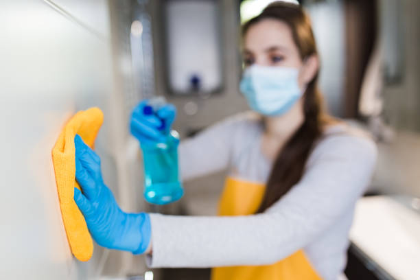 Girl performing a professional cleaning service and cleaning a kitchen wall.