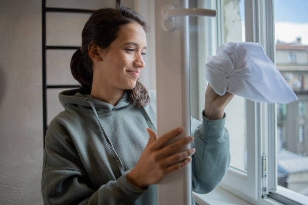 Young professional woman washing office window.