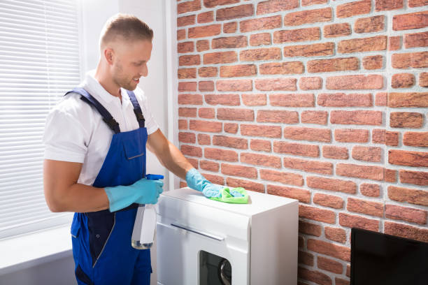 A Happy Cleaner in uniform cleans furniture with a rag and spray for end of lease cleaning.