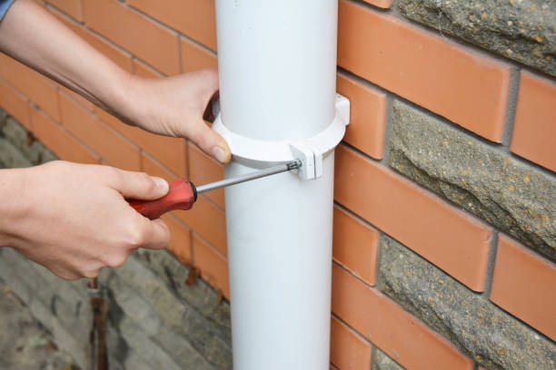 Worker Installing rain gutter downpipe.