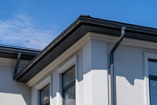 Corner of house with windows, new gray metal tile roof and rain gutter.