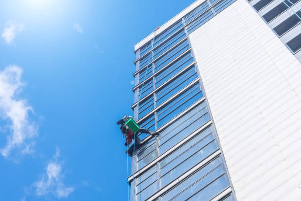 Climber clean windows from the outside of the building washing the glazing of the facade of a multi-storey building.