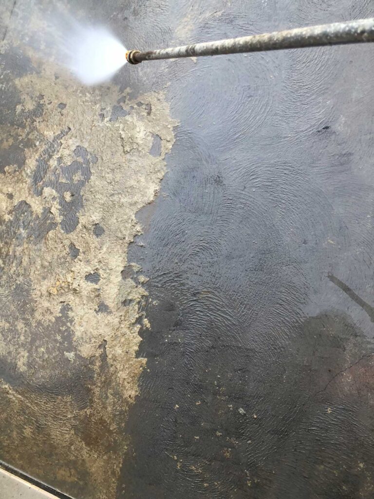 Cleaner using high-pressure washer on a dirty patio.