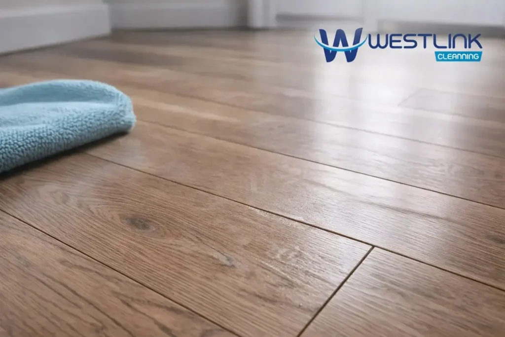 Close-up of laminate floor with haze, streaks, slight seam swelling, and minor bubbling from improper cleaning