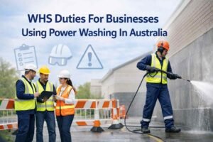 Professional worker safely power washing a surface with PPE and safety barriers, WHS duties for businesses in Australia.