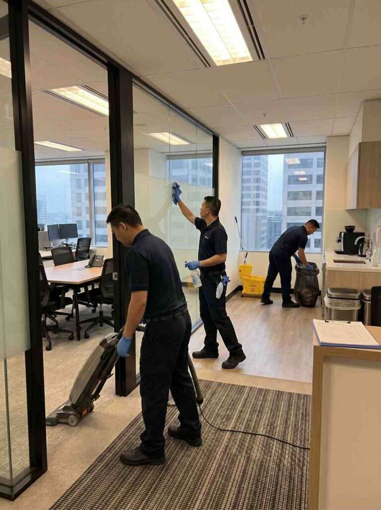Office cleaners working inside a North Sydney office suite with glass partitions, desks, kitchen area and floor cleaning