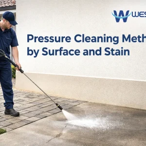 Professional cleaner pressure cleaning a property with concrete, pavers, painted wall, and roof surfaces to show different pressure cleaning methods by surface and stain.